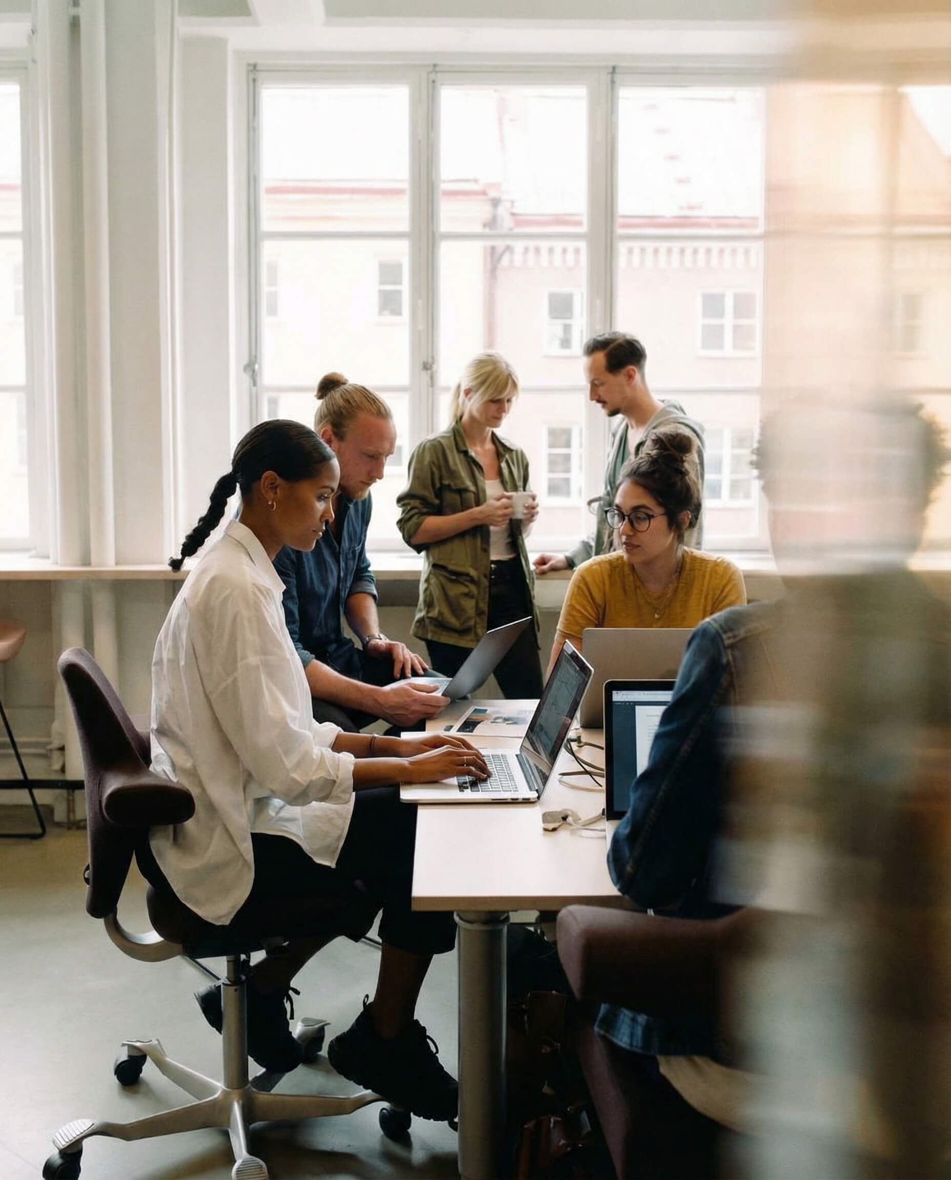 Recruiting team collaborating around laptops in a modern office